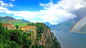 A coastal village with a church, buildings, and a mountain backdrop.