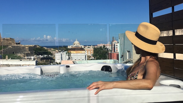 A person relaxing in a hot tub with a view of a cityscape and a large building with a dome.