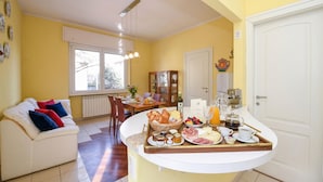 Une cuisine avec un bar pour prendre le petit-déjeuner, un coin repas avec une table et des chaises, et un canapé avec des coussins.