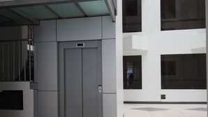 A modern building with a large elevator, glass railings, and a tiled floor. - Mayte Apartment (Cusco)