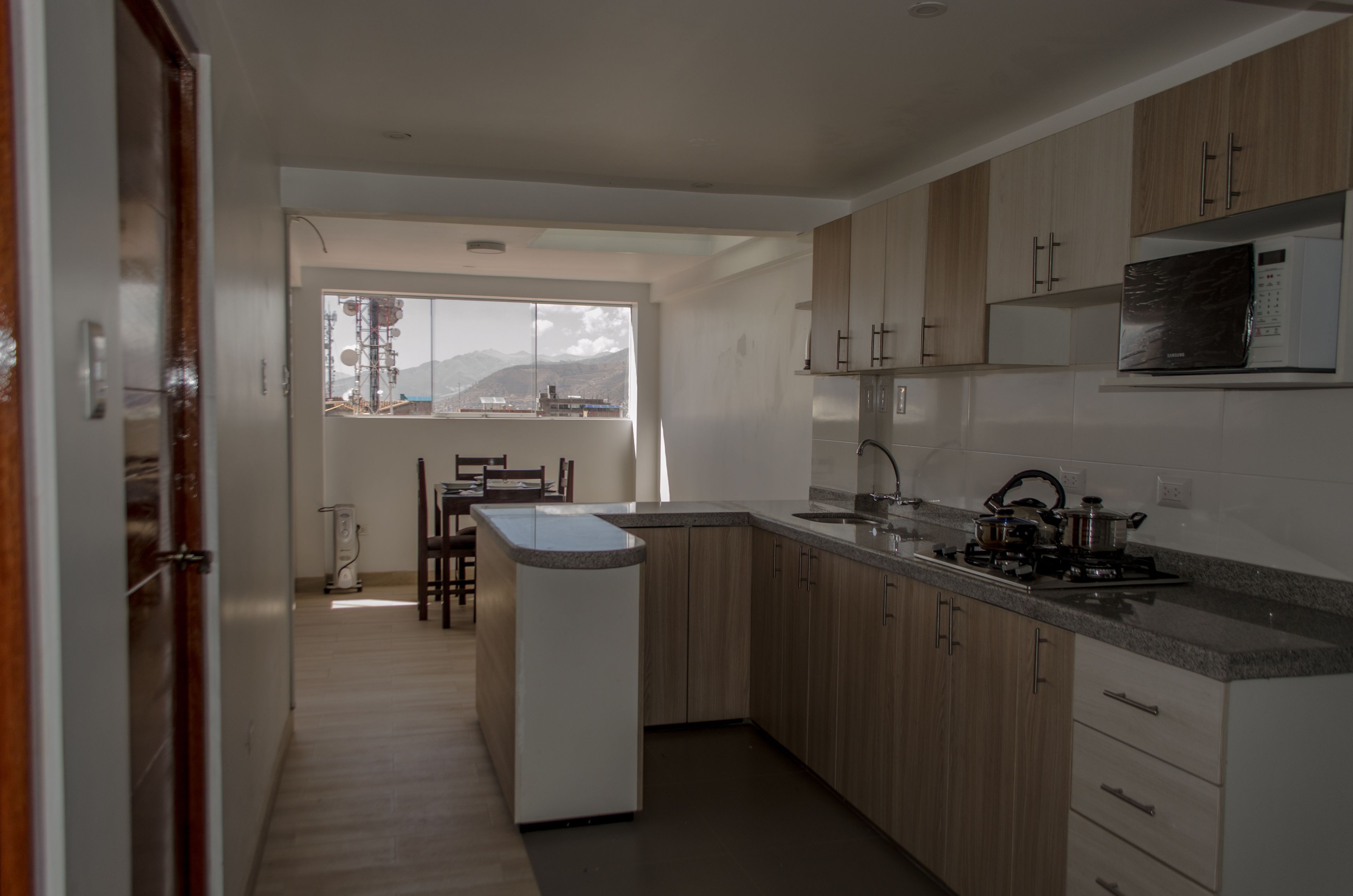 Een moderne keuken met houten kastjes, een ingebouwde kookplaat en een raam met uitzicht op bergen.