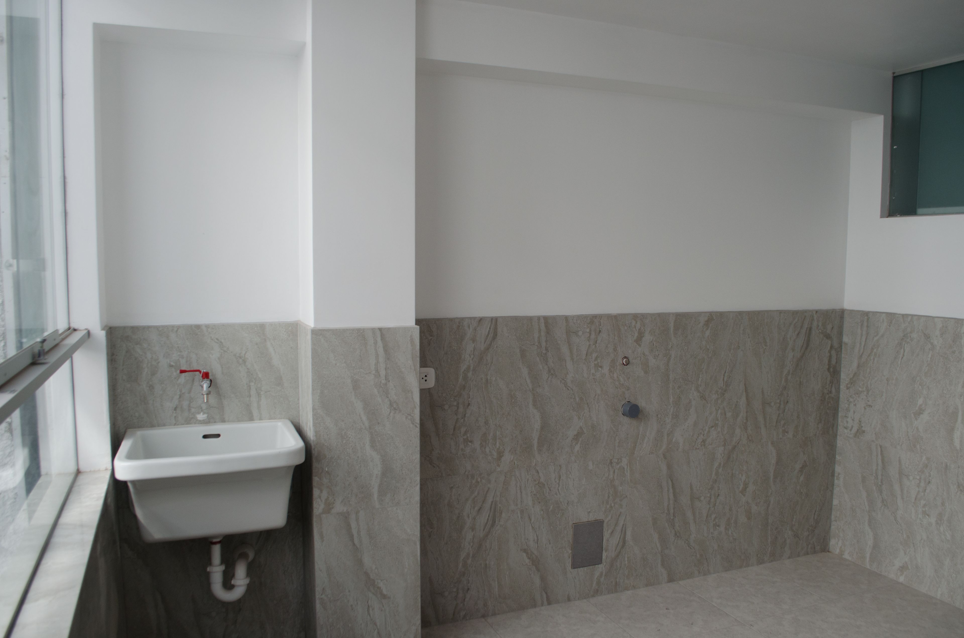 Ein Badezimmer mit weißem Waschbecken, Marmorwänden und einer Duschkabine.