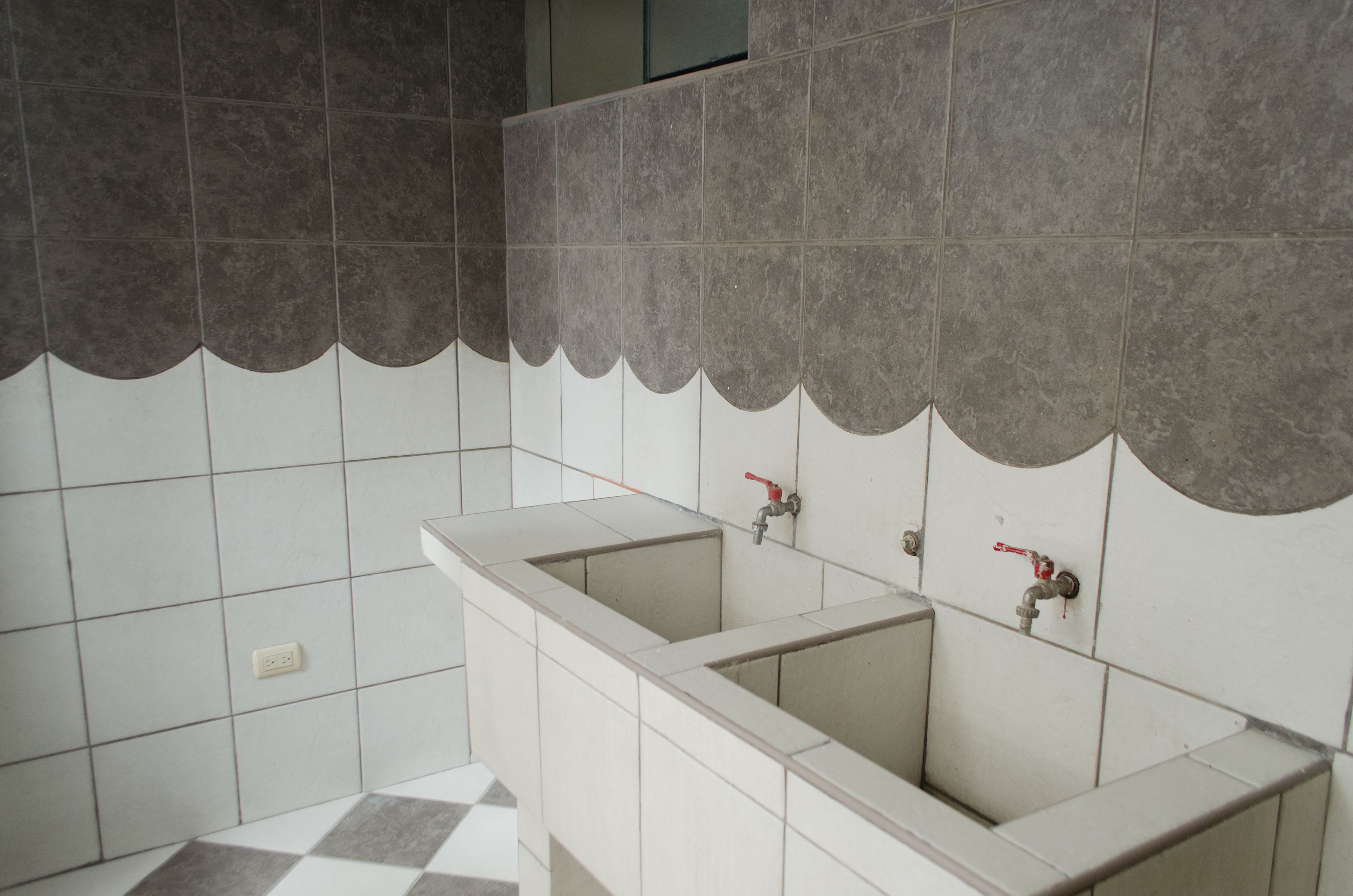 A bathroom with two sinks, tiled walls, and a checkered floor.
