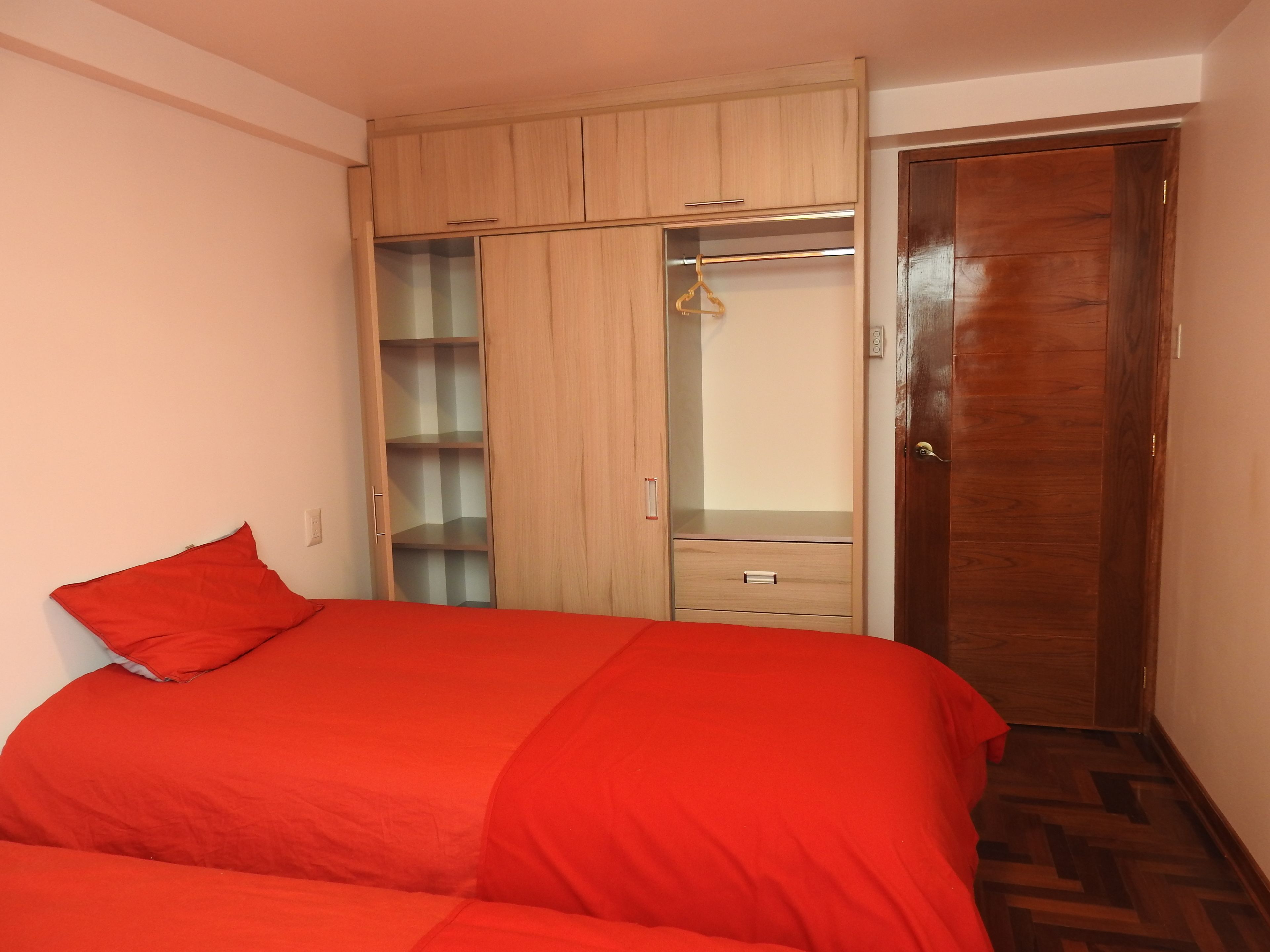 Een slaapkamer met een bed, een kledingkast en een deur.