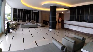 Eine moderne Lobby mit einer Rezeption, einer Sitzecke und einer großen Säule.