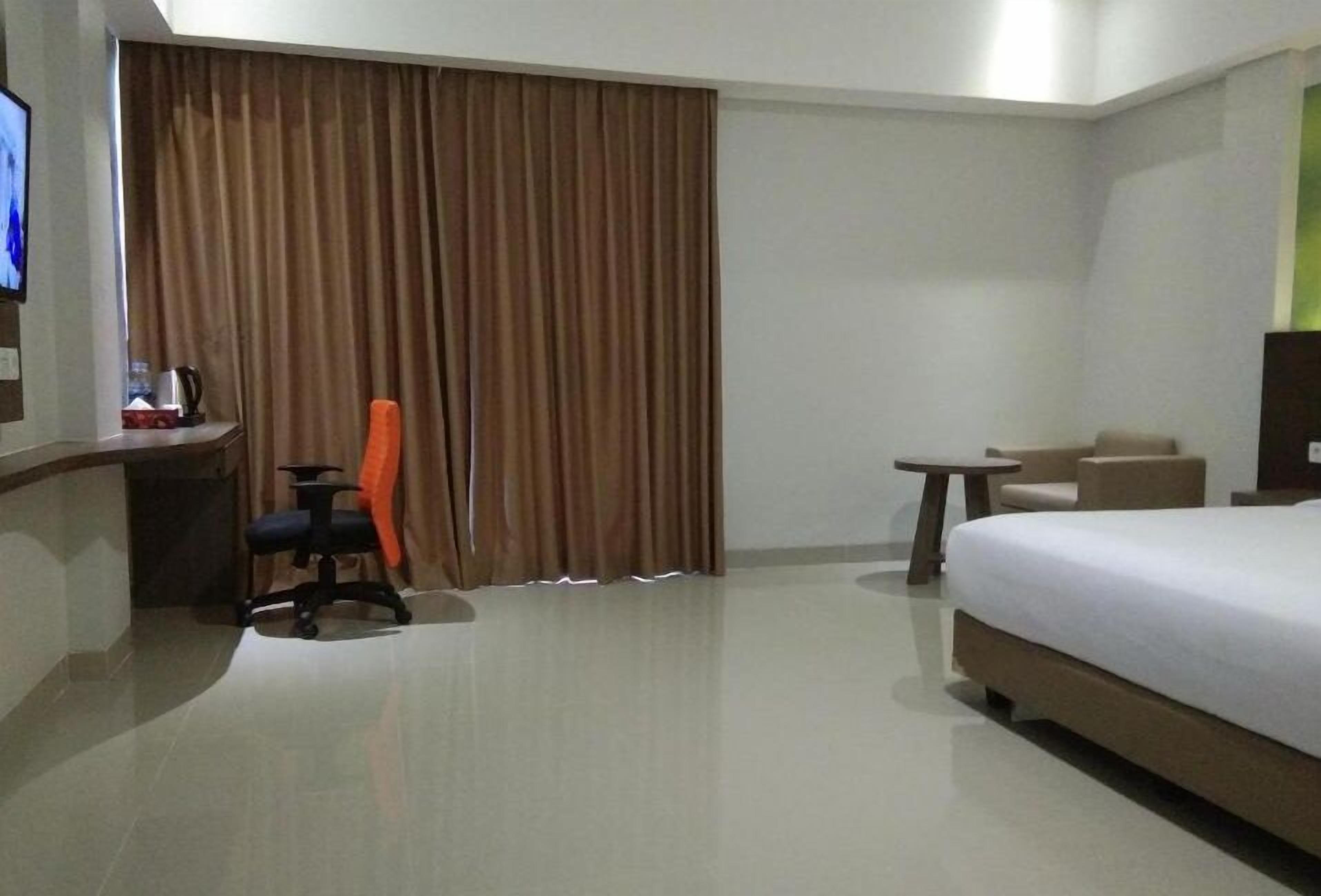 Habitación de hotel con cama, escritorio, silla, mesita y televisor.