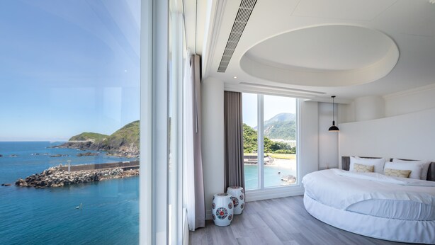 A bedroom with a large window, a bed, and a view of the sea. - Brighthouse (Suao)