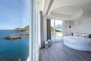 Un dormitorio con una ventana grande, una cama y vistas al mar.