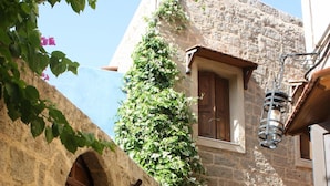A stone building with a wooden door, a window, and a small balcony.