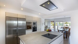 Een moderne keuken met een centraal eiland, roestvrijstalen apparatuur en een eethoek met uitzicht.