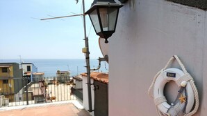 Un balcón con vista al mar, un flotador en la pared y una farola.