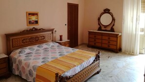Un dormitorio con cama, cómoda, espejo, un cuadro y un equipo de aire acondicionado.