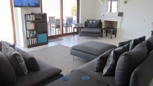 Un salon comprenant un canapé, une table basse, un téléviseur et une bibliothèque.