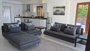Un salon moderne avec un canapé d’angle gris, une table basse et un tapis gris.