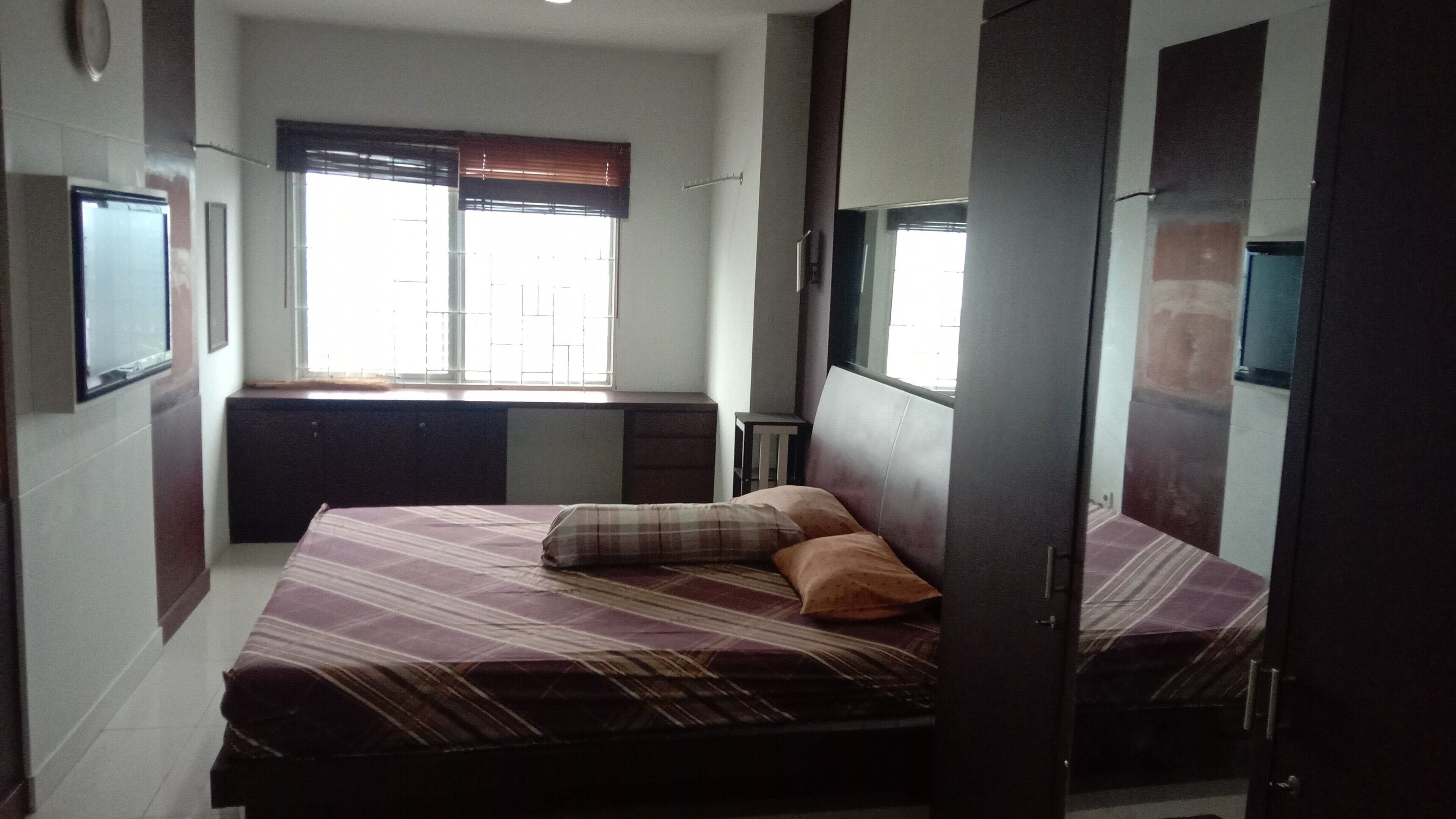 A bedroom with a bed, a dresser, a window with blinds, and a door.