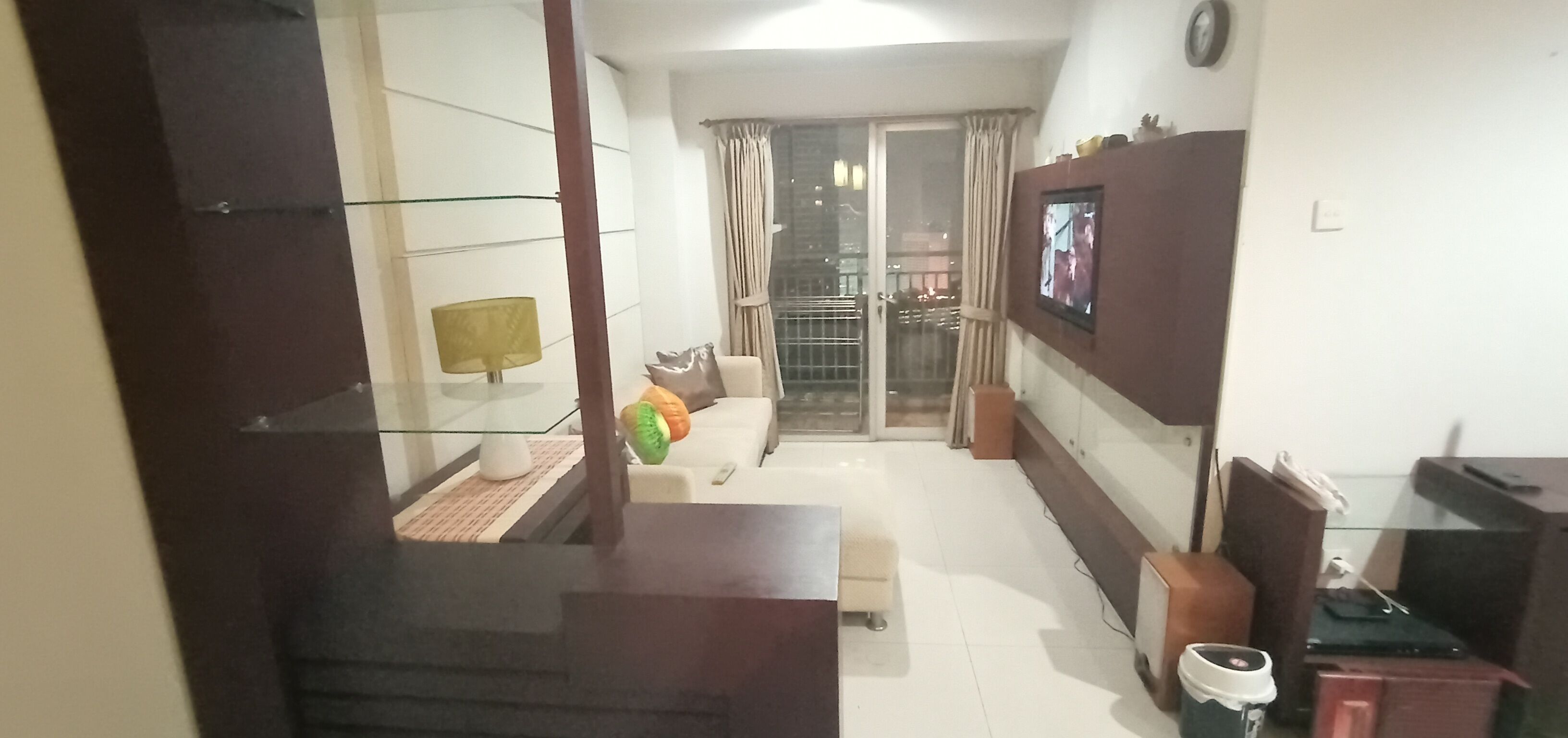 Ein Wohnzimmer mit einer Couch, einem Couchtisch, einem an der Wand befestigten Fernseher und einer Treppe zu einer weiteren Etage.