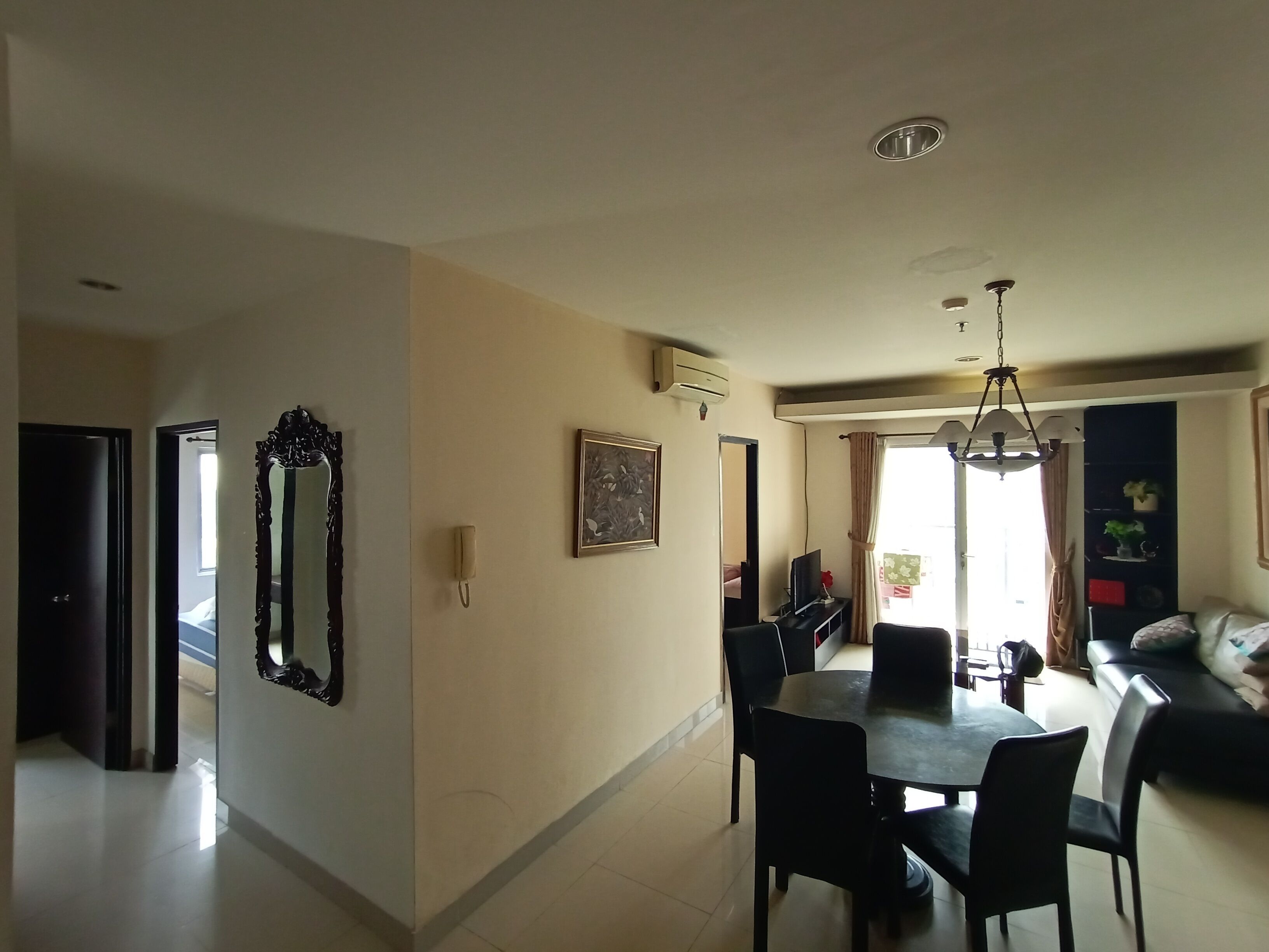 A dining area with a table and chairs, a sofa, and a television.