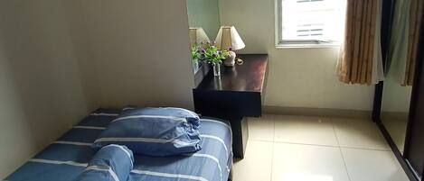A bedroom with a bed, a nightstand, a lamp, and a window with curtains.