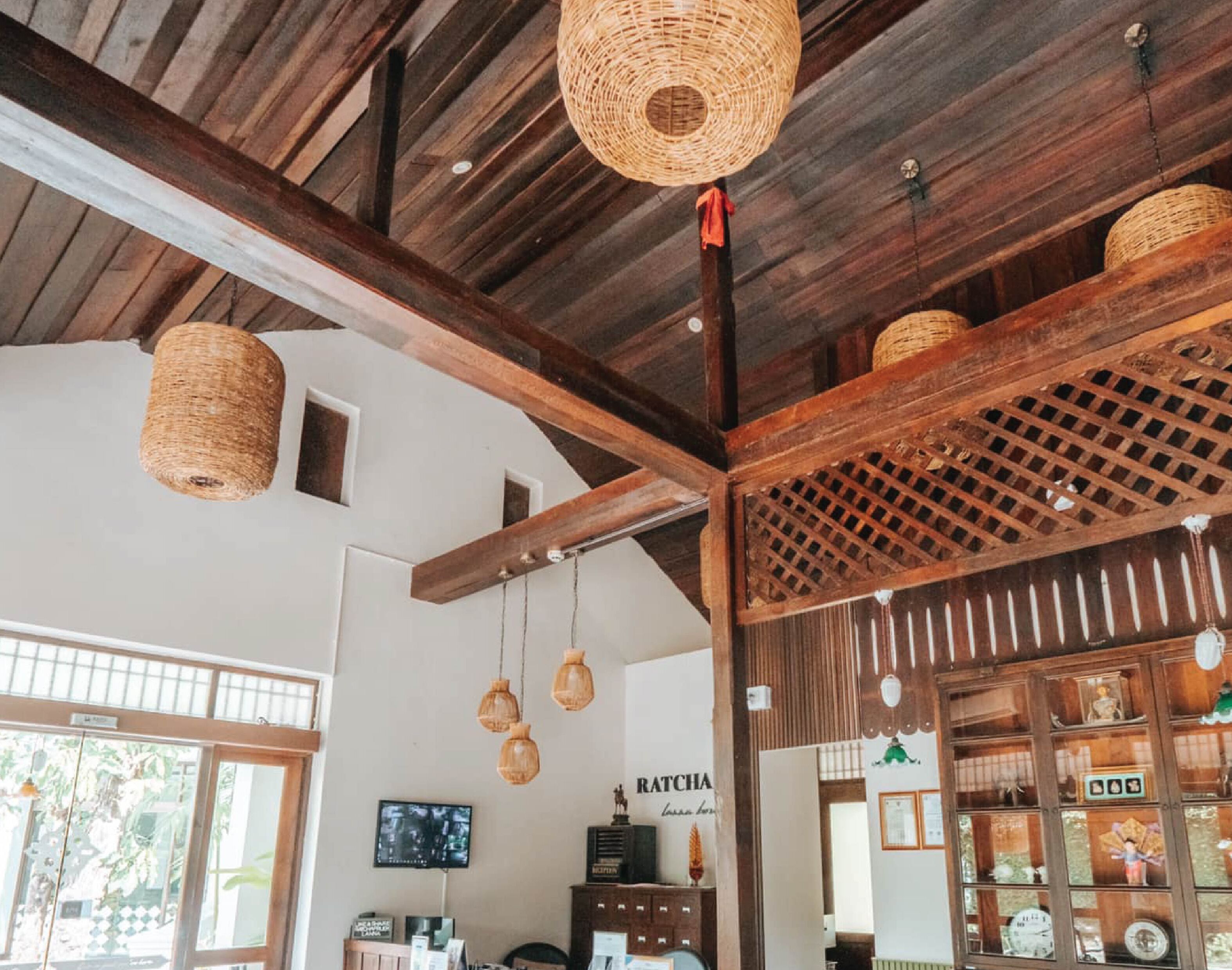 A rustic interior with exposed wooden beams, woven light fixtures, and a traditional Japanese-style cabinet with glass doors.