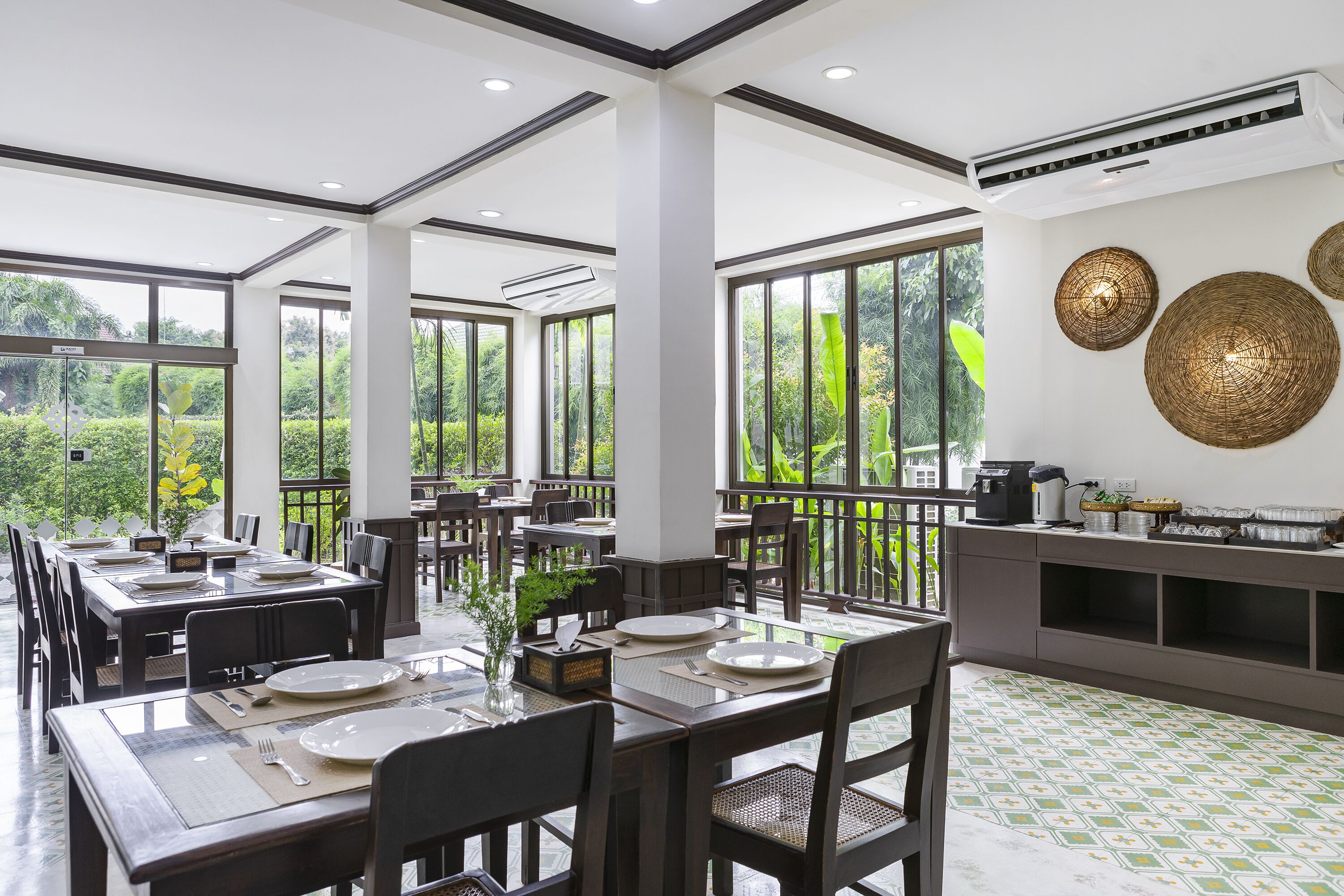 Un'ampia sala da pranzo con grandi finestre, arredi moderni e vista sul verde.