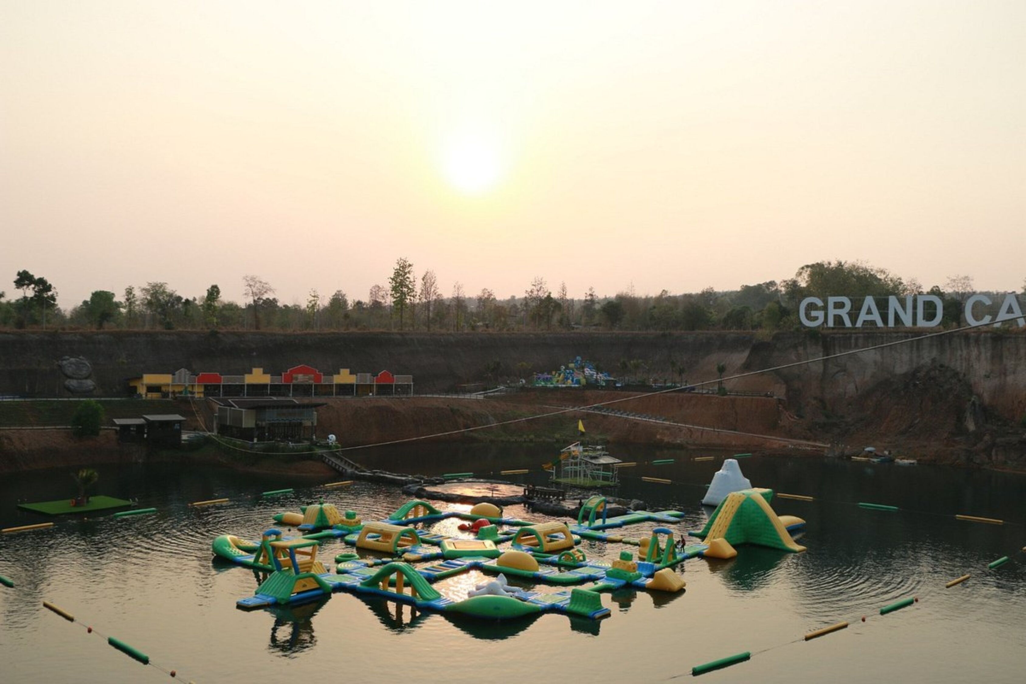 Ein Wasserpark mit aufblasbaren Spielgeräten und einem großen Schild mit der Aufschrift 'GRAND CA'.