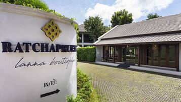 Un panneau indiquant la direction de Ratchaphrue, une flèche directionnelle, un chemin pavé et un bâtiment avec un toit en tuiles.