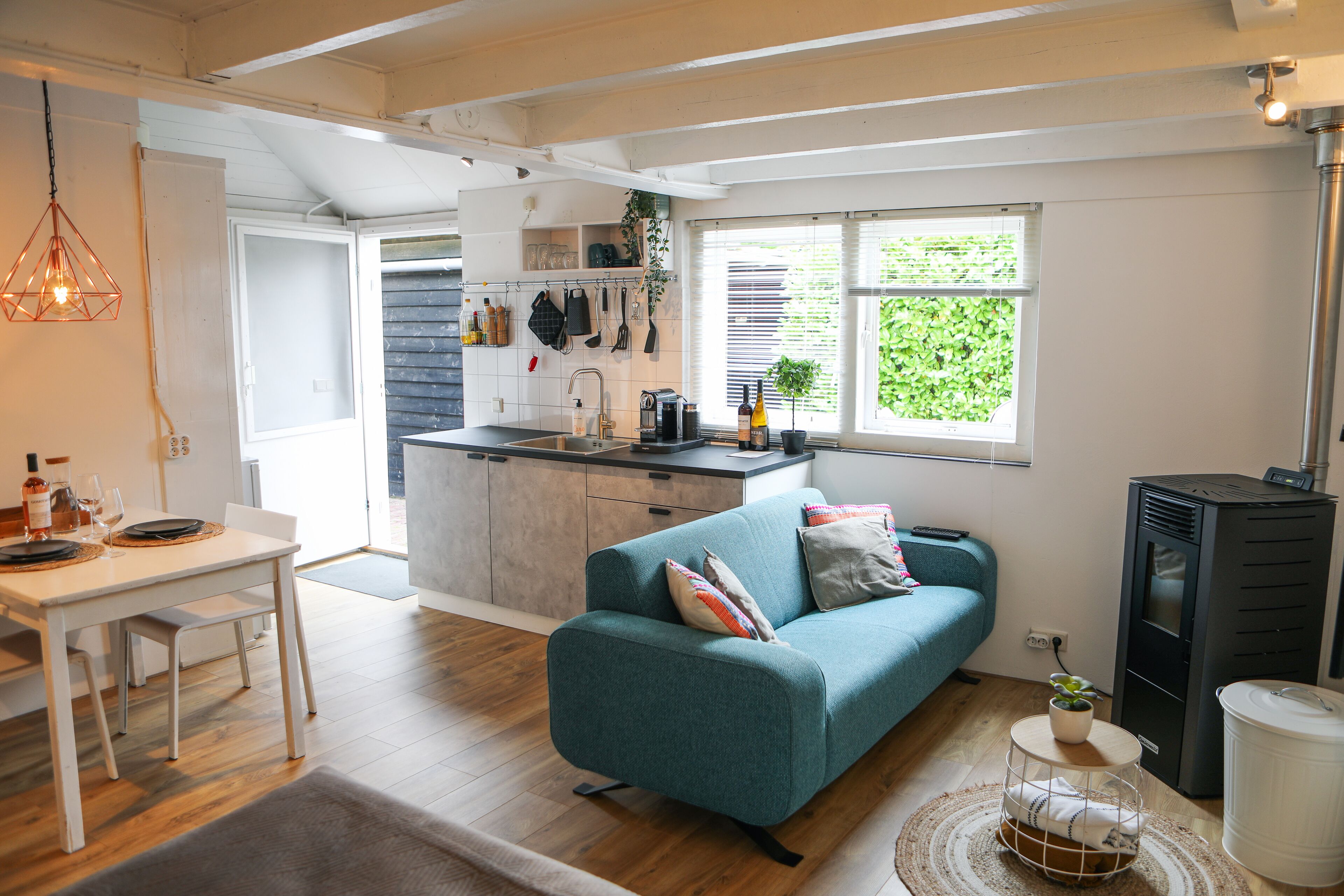A modern kitchen with a dining area, a sofa, and a small plant.