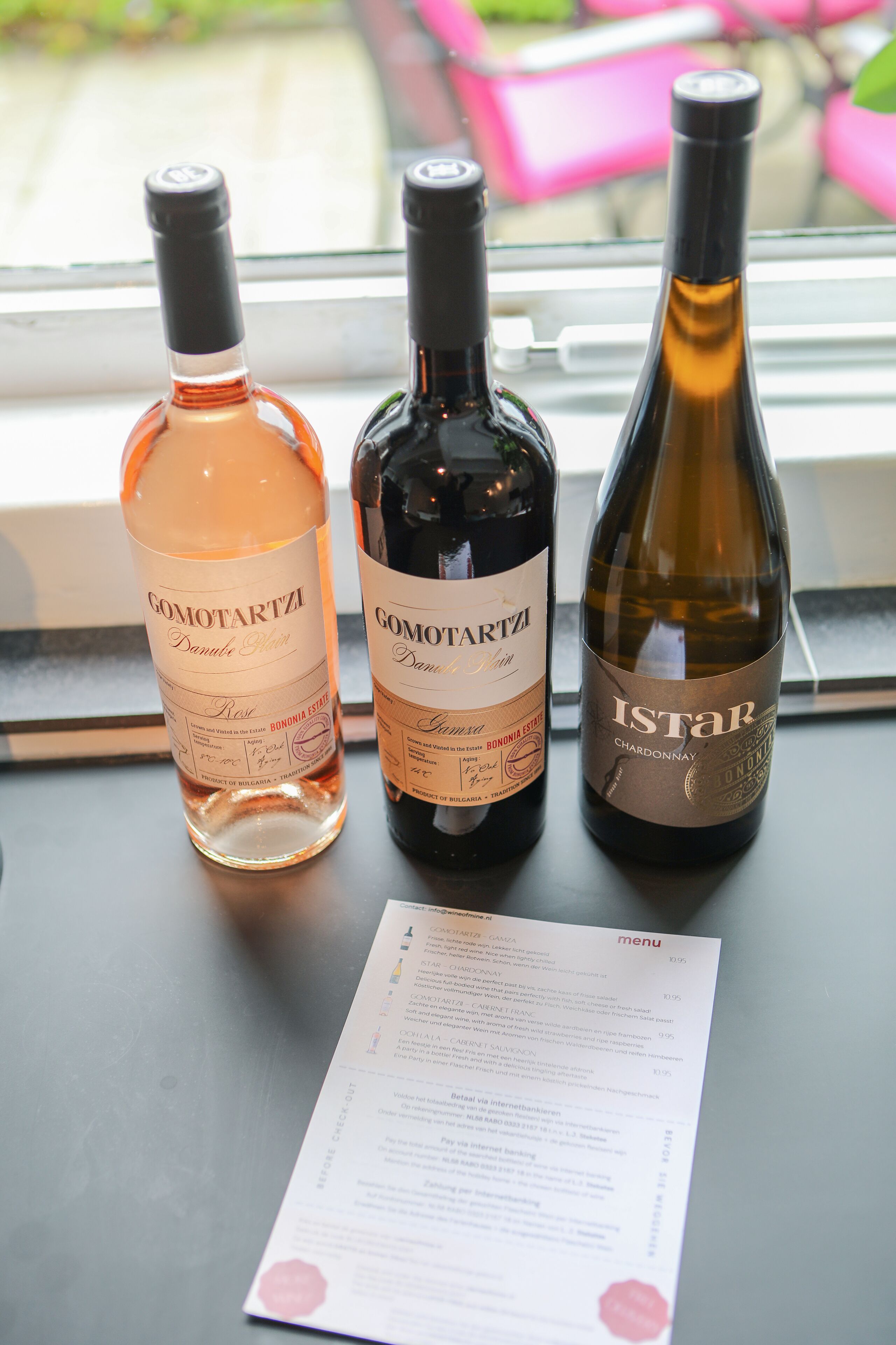 Trois bouteilles de vin sont posées sur une table, avec un menu devant.