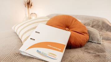 A neatly arranged bed with a white folder labeled "Blue Green Holiday" and a brown pillow.