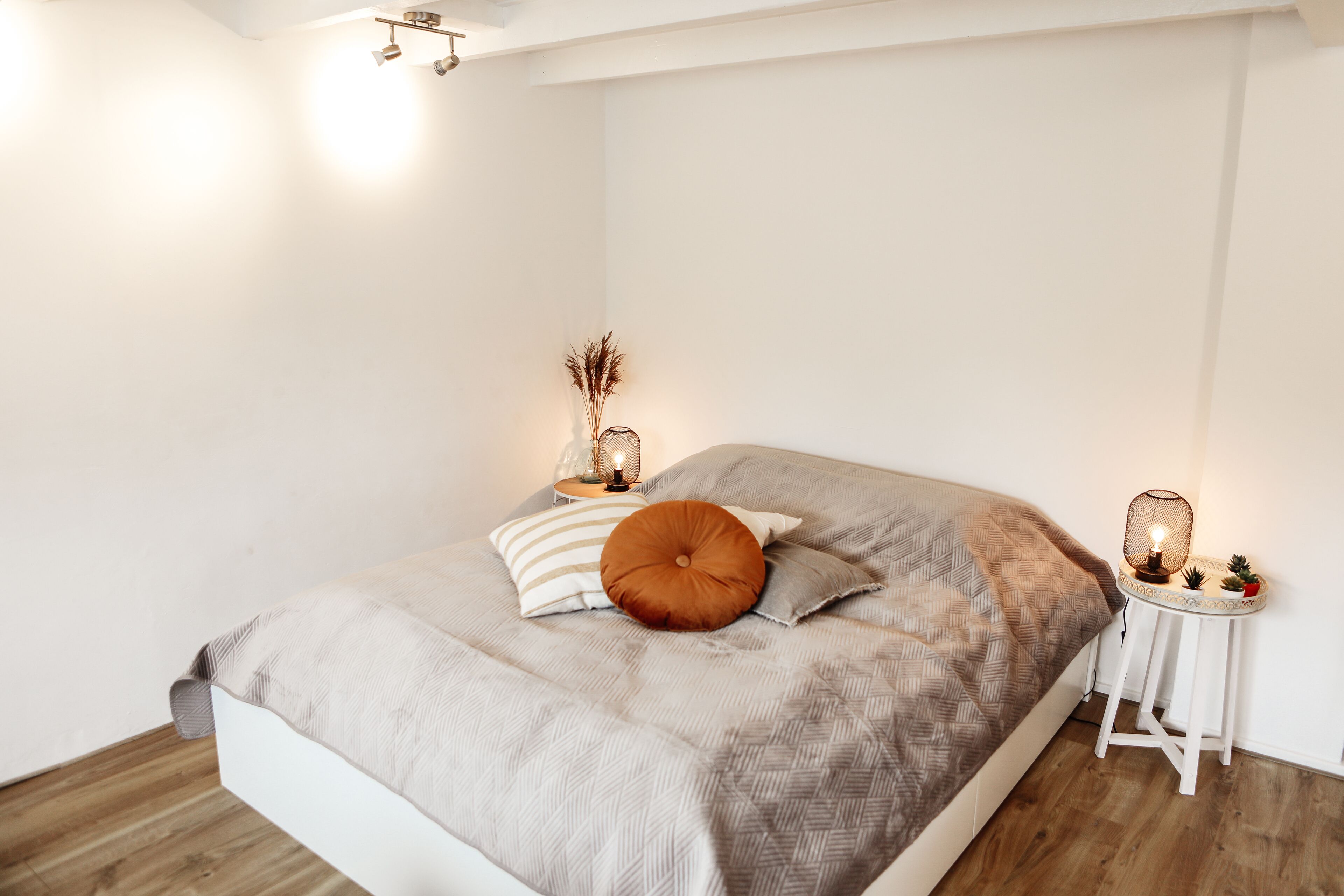 A bedroom with a bed, bedside tables, and wall-mounted lights.