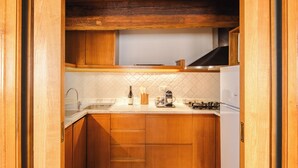 A compact kitchen with wooden cabinets, a countertop, a sink, and a stove. - Elegant two-bedroom apartment in the very heart of Rome. Perfect for a family! (Roma)