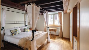 A bedroom with a four-poster bed, wooden flooring, a window with curtains, and a bedside table. - Elegant two-bedroom apartment in the very heart of Rome. Perfect for a family! (Roma)