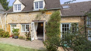 A stone house with a traditional design, featuring a front door, two windows, and a small porch area. - Pilgrim Cottage - sleeps 8 guests  in 4 bedrooms (Bourton-on-the-Hill)