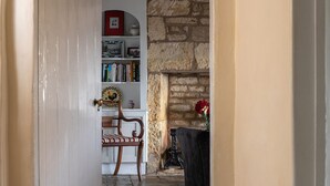 A room with a bookshelf, a chair, and a fireplace. - Pilgrim Cottage - sleeps 8 guests  in 4 bedrooms (Bourton-on-the-Hill)