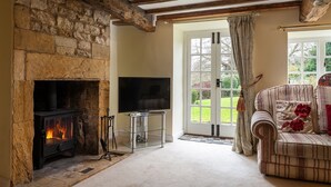 A cozy living room with a stone fireplace, a flat-screen TV, and a comfortable sofa. - Pilgrim Cottage - sleeps 8 guests  in 4 bedrooms (Bourton-on-the-Hill)