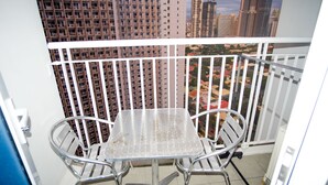 A balcony with a metal table and chairs, a white railing, and a view of high-rise buildings. - SM Jazz Residence by Good Rent (Makati)