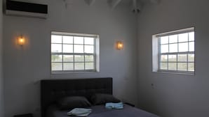 A bedroom with a large bed, two windows, and a ceiling fan. - Villa Sol, luxury fully equipped villa with wifi, a short distance from the sea (Kralendijk)