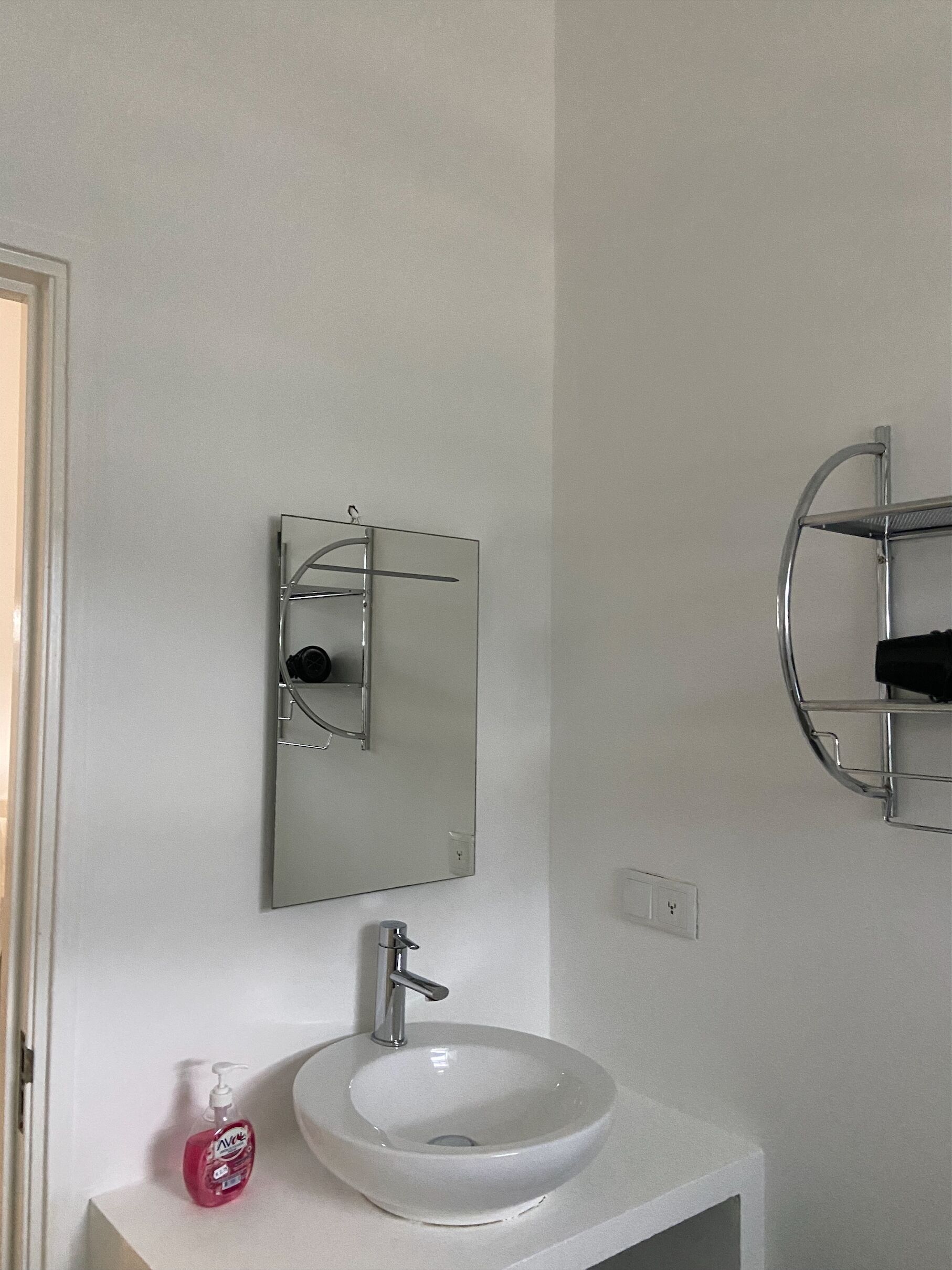 Un bagno con un lavandino bianco, uno specchio e un porta asciugamani cromato.