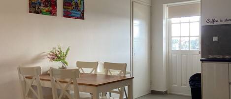 Un coin repas avec une table et des chaises, une petite plante et deux œuvres d’art colorées accrochées au mur.