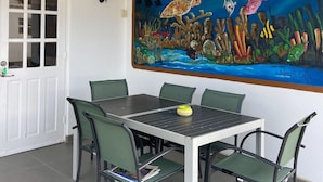 A dining area with a table and chairs, a painting of an underwater scene, and a white door with glass panels. - Villa Sol, luxury fully equipped villa with wifi, a short distance from the sea (Kralendijk)
