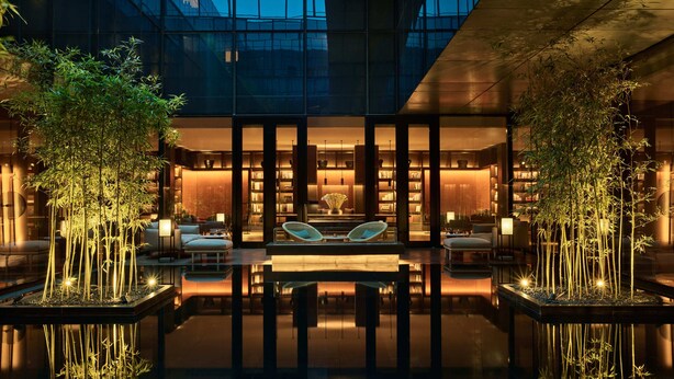A modern building with a glass facade, a central atrium with seating, and bamboo plants. - The PuXuan Hotel and Spa (Beijing)