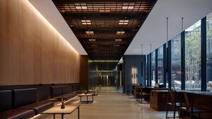 A modern interior with wooden panel walls, a long bench seating area, and a reception desk with chairs. - The PuXuan Hotel and Spa (Beijing)