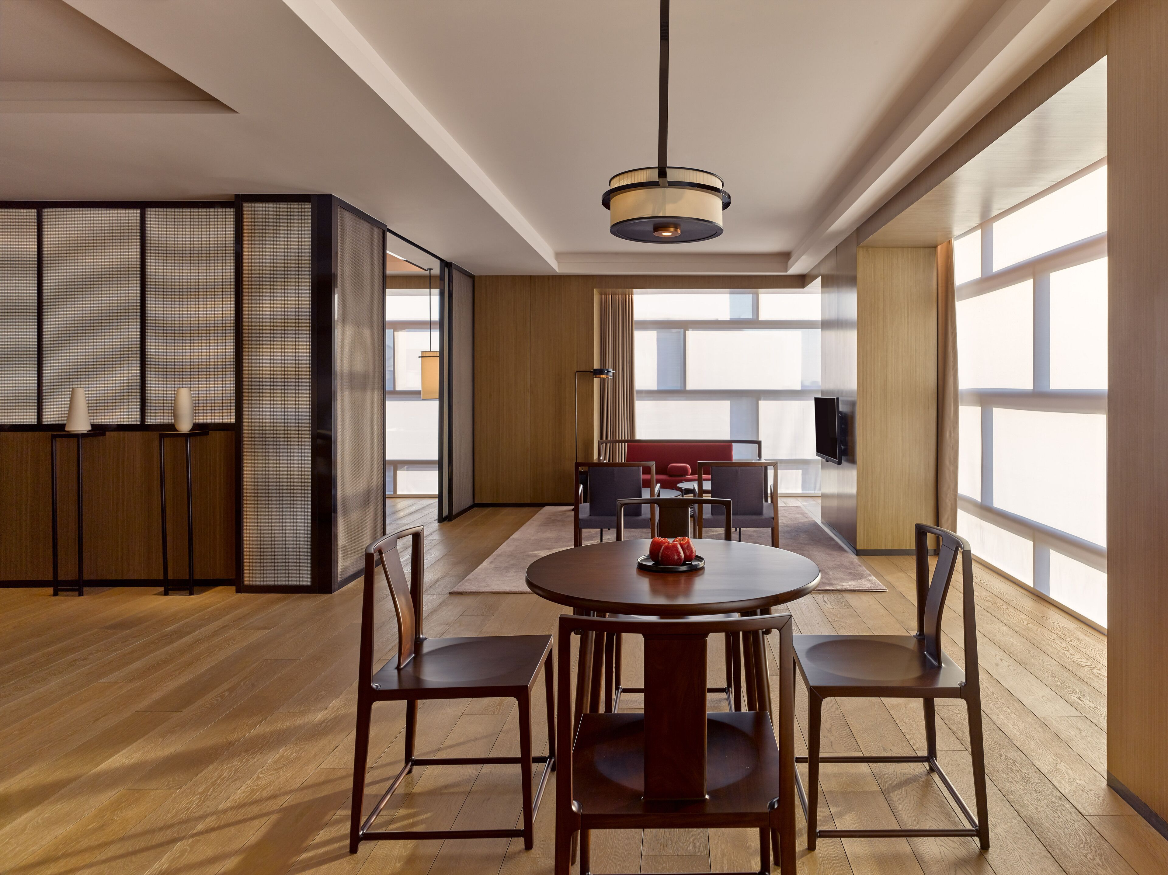 Un espace repas moderne avec une table ronde, quatre chaises et un luminaire suspendu.