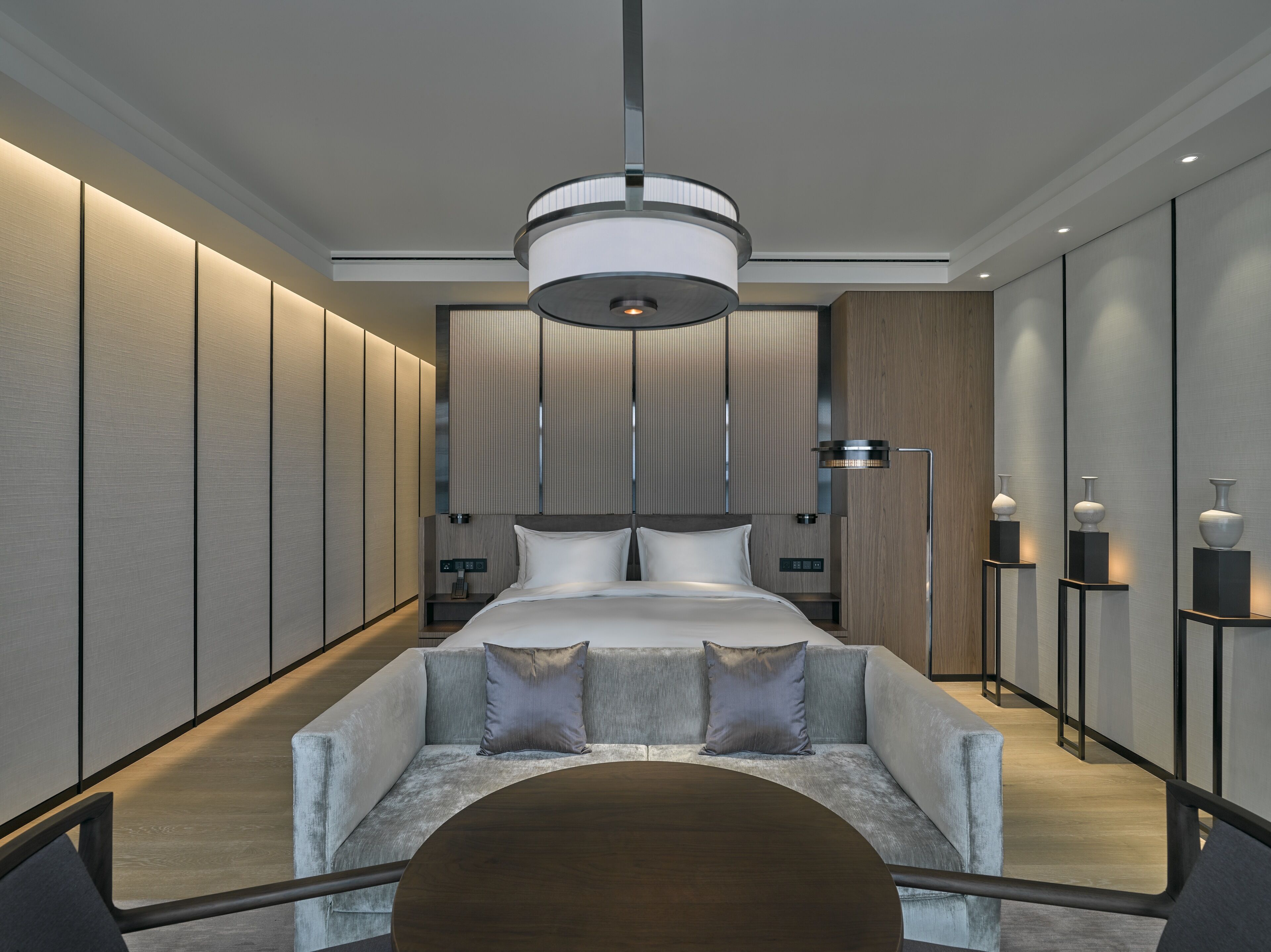 Una habitación de hotel moderna con una cama grande, un sofá, un escritorio y una mesita de noche.