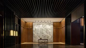 A modern lobby with a polished floor, wooden paneling, and a large wall mural.