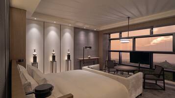 Een moderne hotelkamer met een groot bed, een bureau en een televisie. Door het raam is er uitzicht op de bergen.