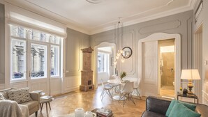 A spacious living room with a fireplace, a dining area, and a modern kitchen visible through an open door.