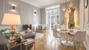A spacious living room with a sofa, a coffee table, a TV, and a dining area with chairs and a table.