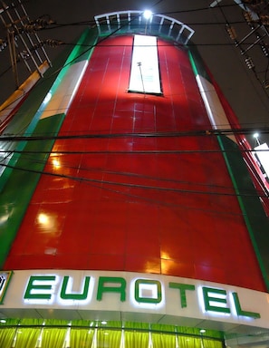 Um sinal luminoso da Eurotel, com chão vermelho e verde, fios elétricos e teto branco.