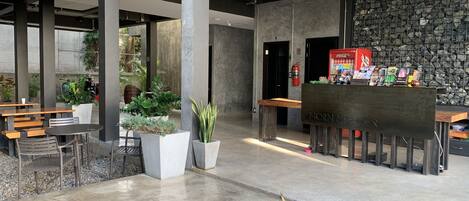 Un espacio interior moderno con pilares de concreto, zonas de estar y una pared de piedra.